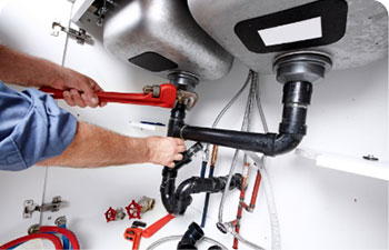 A plumber fixing kitchen sink pipes.