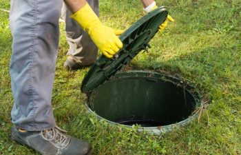 A technician removing a septic tank lid.