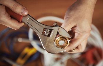 Plumber With Adjustable Wrench on a Nut
