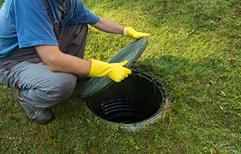 A septic company worker opening a septic tank lid.