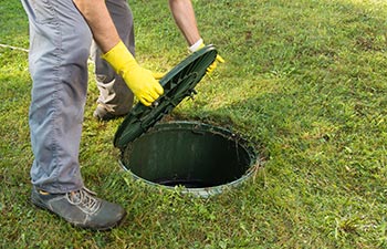 A septic company worker opening a septic tank lid.