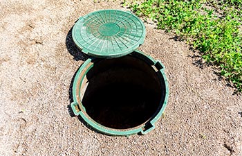A lid next to an open septic tank.