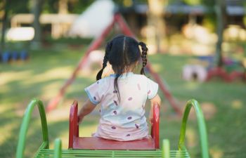 Little girl playing on a slide in a garden.