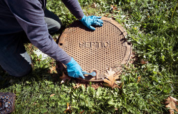 A working plumber opening septic system tank