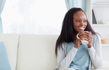 smiling woman with a mug in hand sitting on the couch